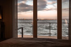 A room with a large window overlooking a body of water and a distant cityscape. - Holiday home with 2 bedrooms (Bitterfeld)