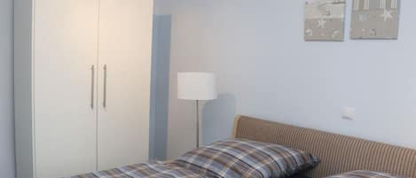 Quarto com cama, guarda-roupa e abajur.