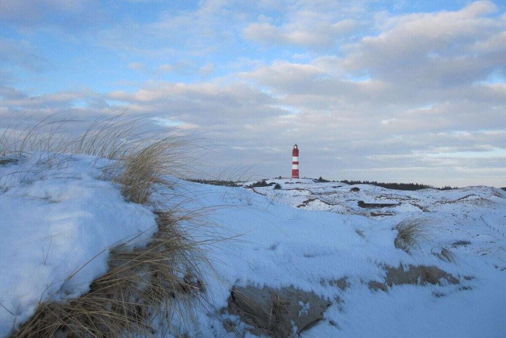 A lighthouse on a snow-covered landscape with a clear sky.