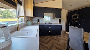 A compact kitchen with a sink, stove, and cabinets. - Killymoon Lodge – Luxury Adults-Only Escape with Private Hot Tub (Newport)