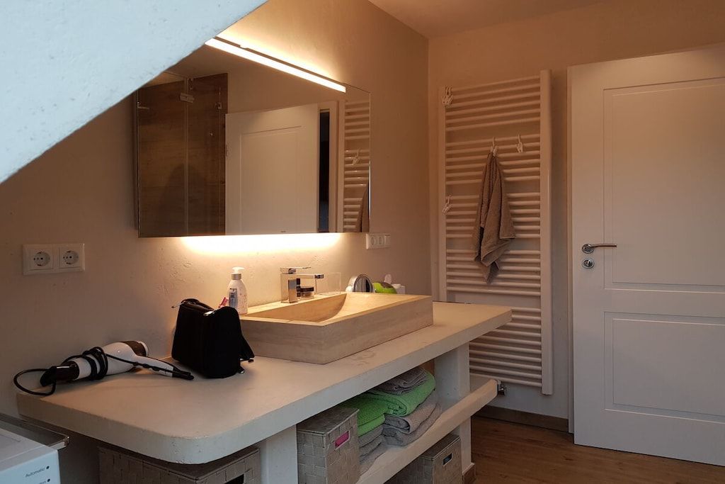 A bathroom with a sink, mirror, towel rack, and a door.