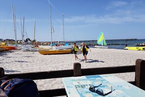 Ein Strand mit Booten und Spaziergängern.