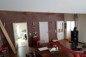 Ein Wohnzimmer mit einer Couch, einem Tisch, einem Kamin und einer Tür zu einem anderen Raum.