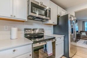 A modern kitchen with stainless steel appliances, white cabinetry, and a wooden countertop. - Capstan Terrace - Fully Furnished 3-Story Townhome with Garage and Private Patio in Charlotte (Charlotte)