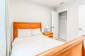 A neatly made bed with a wooden headboard, a bedside table with a lamp, and a closet with hanging space. - Capstan Terrace - Fully Furnished 3-Story Townhome with Garage and Private Patio in Charlotte (Charlotte)