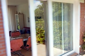 Ein Zimmer mit Essbereich, einer Schiebetür zu einem Balkon und einer Außenwand aus Ziegelsteinen.