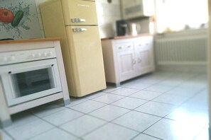 Eine Küche mit einem weißen Ofen, einem beigen Kühlschrank und einer Mikrowelle.