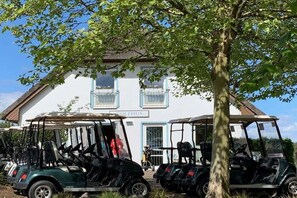 A building with a sign reading 'GOLFUS' and several golf carts parked in front. - Residence on Balmer Lake RadundMeer (Balm\/Usedom)