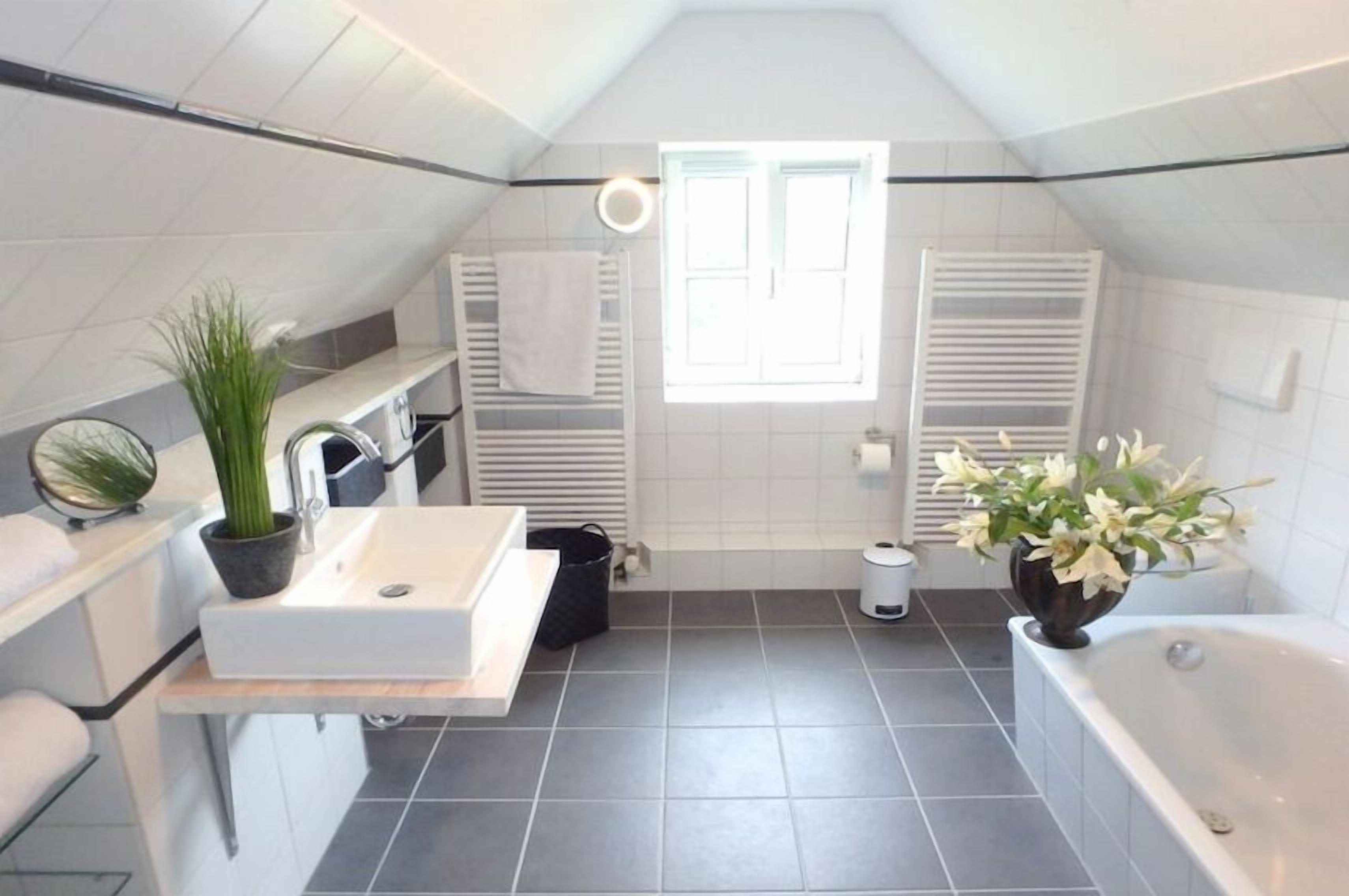 A modern bathroom with a bathtub, a sink, and a window.