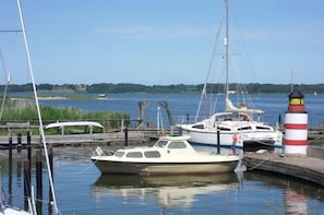 Ein Yachthafen mit vertäuten Booten, einem Leuchtturm und ruhigem Wasser.