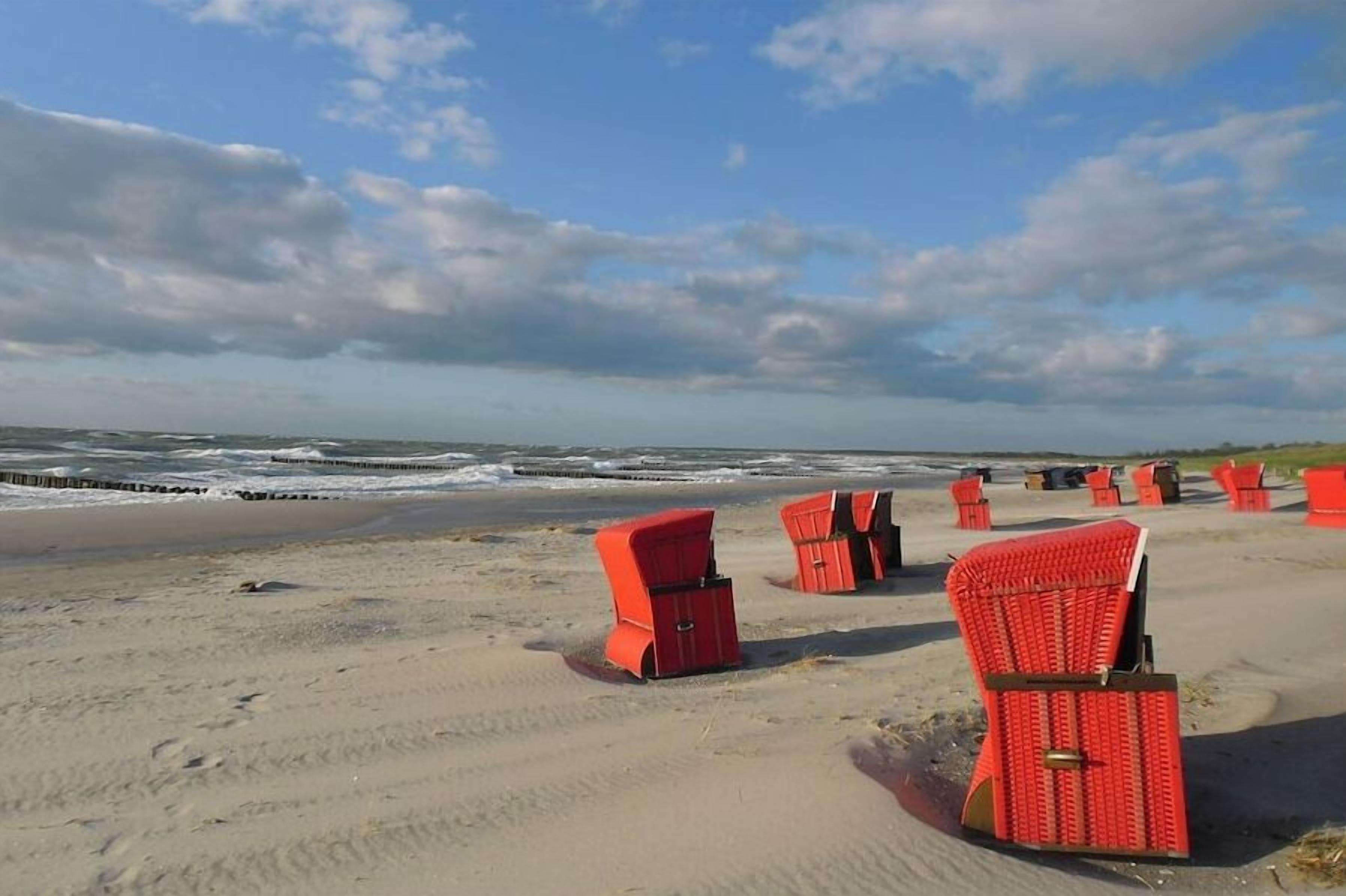 Een strand met rode stoelen op een rij, gericht op de oceaan.