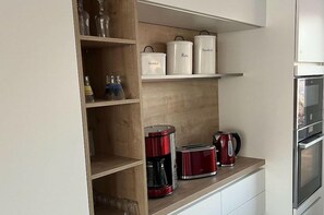 A kitchen with wooden shelves, a coffee maker, a toaster, and a kettle. - Holiday home with 3 bedrooms (Bitterfeld)