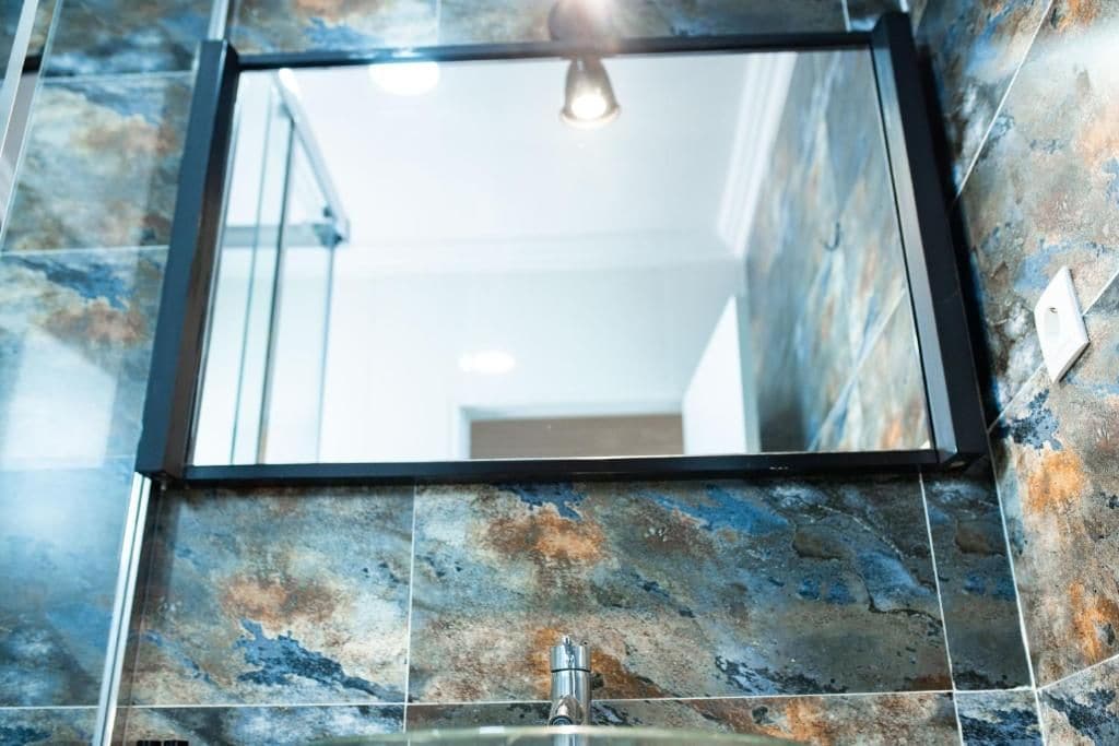 A bathroom with a mirror, sink, and a light fixture.