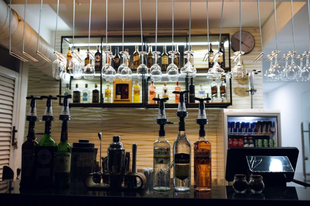 A bar area with multiple liquor bottles, glasses, and a cash register.
