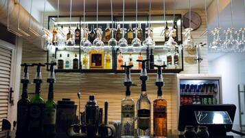 A bar area with multiple liquor bottles, glasses, and a cash register.