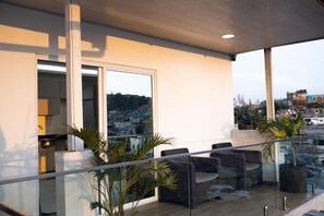 A modern balcony with glass railings, seating, and potted plants. - Alojamento Local Onzo Yamy (Luanda)
