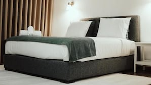 A modern hotel room with a bed, a nightstand, a wall-mounted air conditioner, and a window with blinds. - Alojamento Local Onzo Yamy (Luanda)