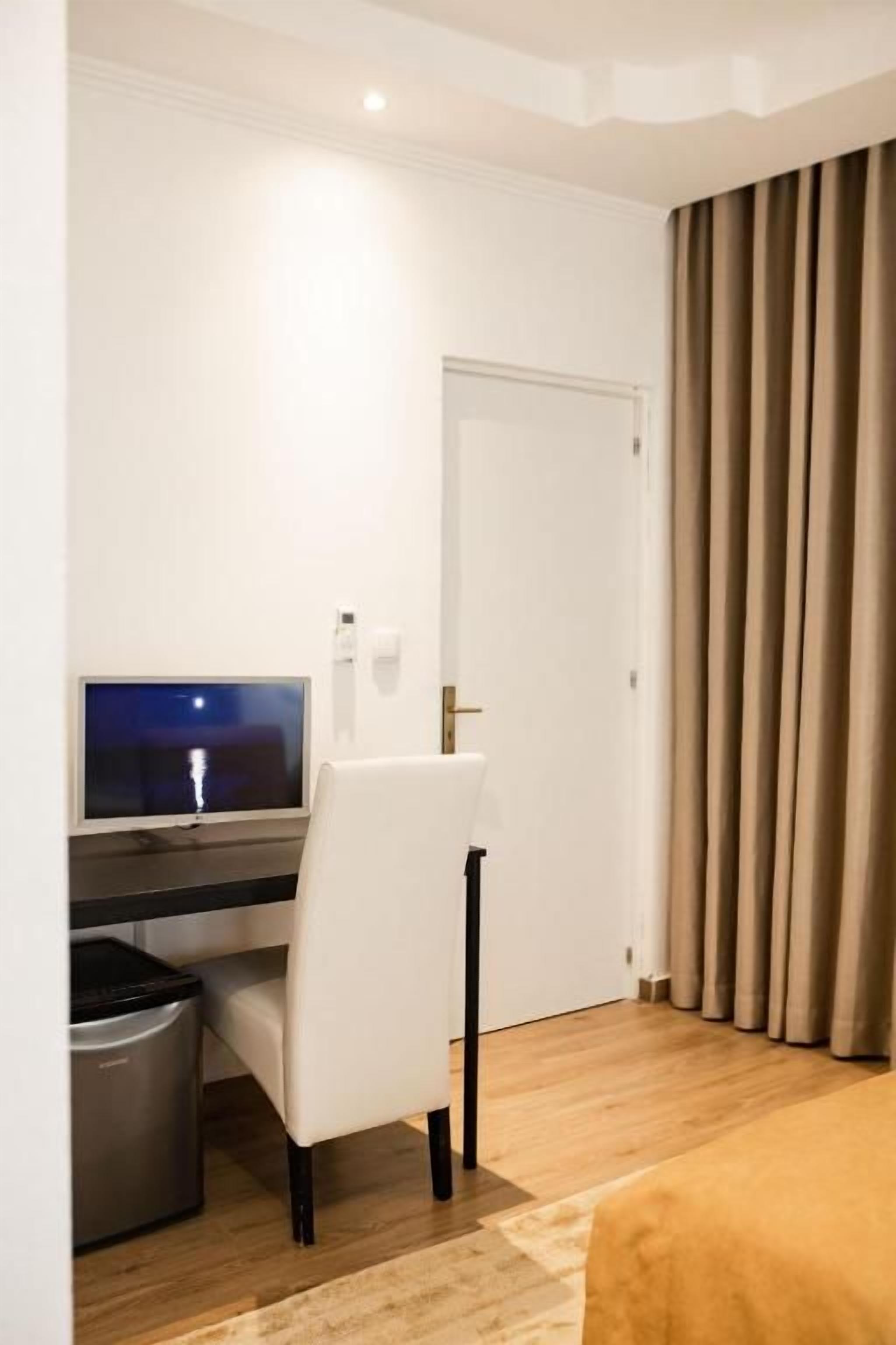 Ein Hotelzimmer mit Schreibtisch, Stuhl und Fernseher.