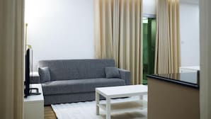 A modern living room with a grey sofa, a white coffee table, and beige curtains. - Alojamento Local Onzo Yamy (Luanda)