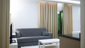 Uma sala de estar moderna com um sofá cinzento, uma mesa de centro branca e cortinas bege.