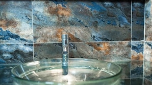 A bathroom with a glass sink and a faucet. - Alojamento Local Onzo Yamy (Luanda)