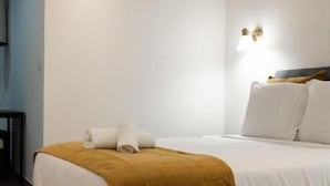 A hotel room with a bed, a bedside table, and a wall-mounted light fixture. - Alojamento Local Onzo Yamy (Luanda)