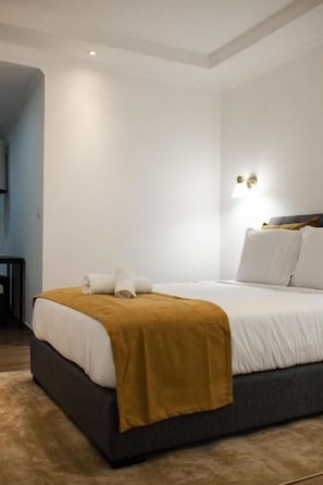 Et hotelværelse med en seng, et sengebord og en lampe monteret på væggen.