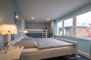 Ein Schlafzimmer mit Etagenbett, Nachttisch mit Lampe und Fenster mit Blick nach draußen.