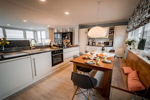 A modern kitchen with a dining area, wooden flooring, and a large window providing natural light. - Holiday home with 2 bedrooms (Bitterfeld)