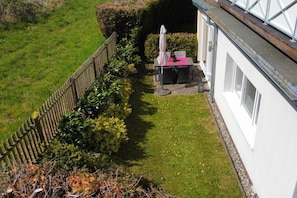 A fenced garden with a table and chairs, a white building, and a hedge. - Holiday apartment with 1 bedroom (Ostseebad Boltenhagen - Tarnewitz)