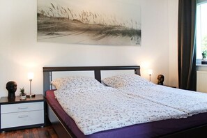 Ein Schlafzimmer mit einem Bett, Nachttischen, einer Lampe und einem an der Wand hängenden Gemälde.