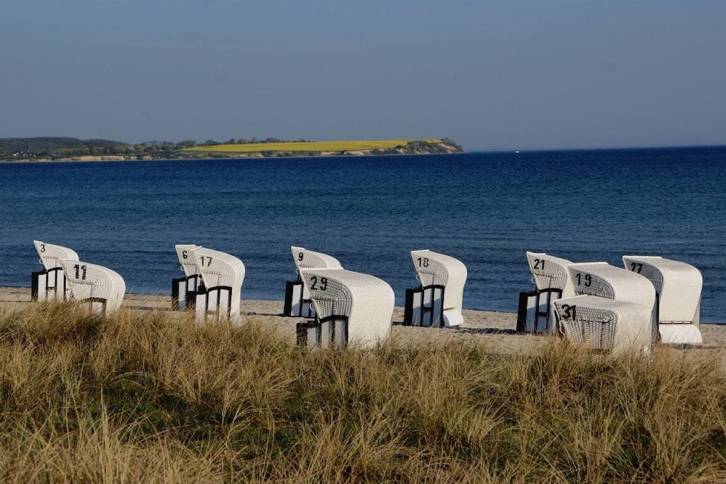 Beach chairs numbered 3 to 27 arranged on a sandy beach with the ocean in the background.
