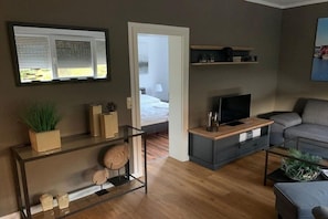 A modern living room with a sofa, TV, and a console table with decorative items. - Holiday apartment with 1 bedroom (Ostseebad Boltenhagen - Tarnewitz)