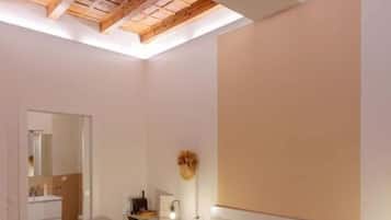 Ein Schlafzimmer mit einem großen Bett, einer Holzbalkendecke, einem Nachttisch mit Lampe und einem Spiegel.