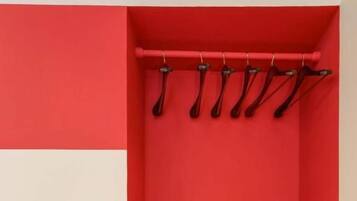 Una habitación con una pared roja, una maleta verde y un equipo de aire acondicionado blanco.