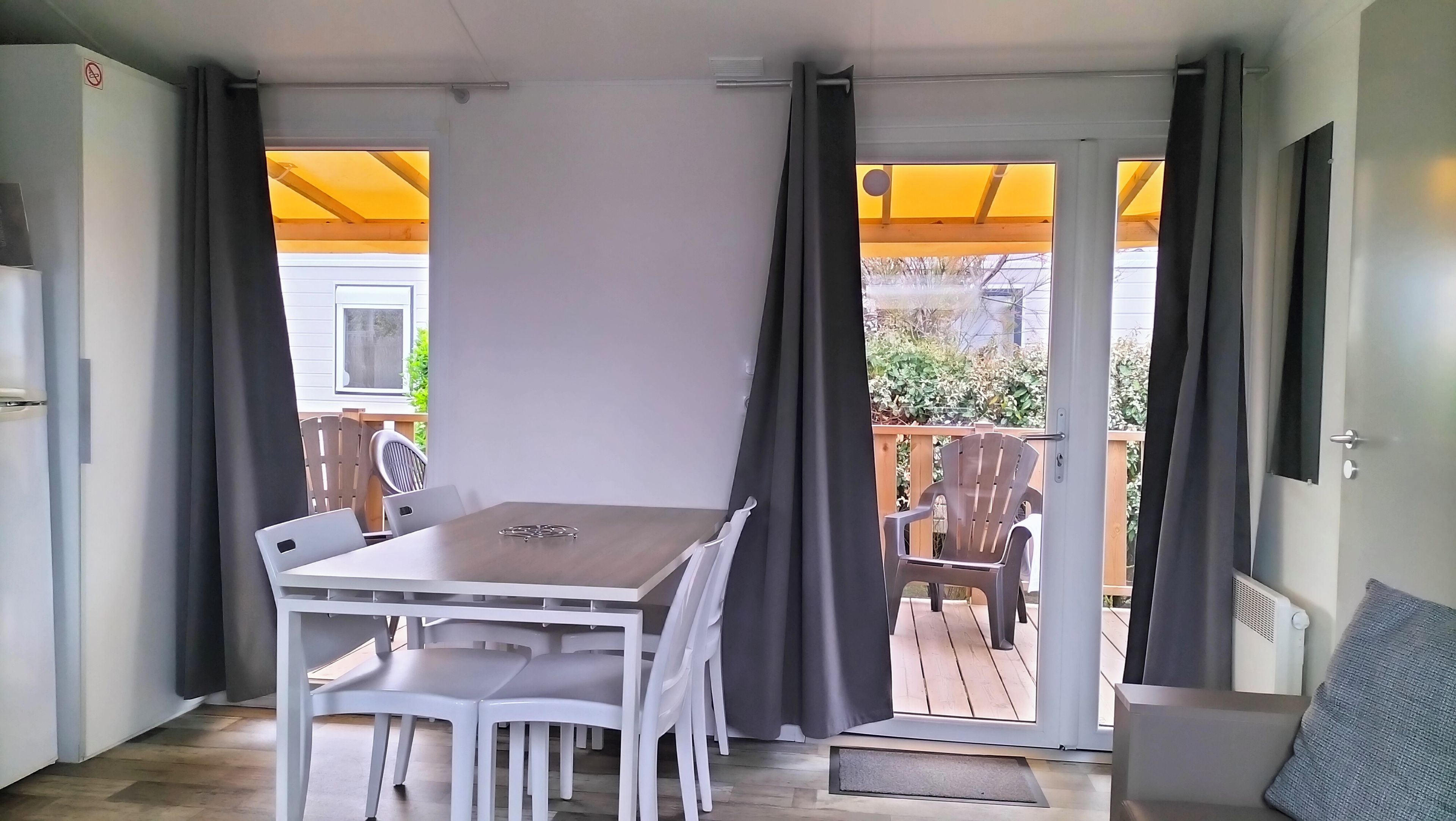 A room with a table and chairs, a sliding door leading to an outdoor area with a wooden deck and chairs.