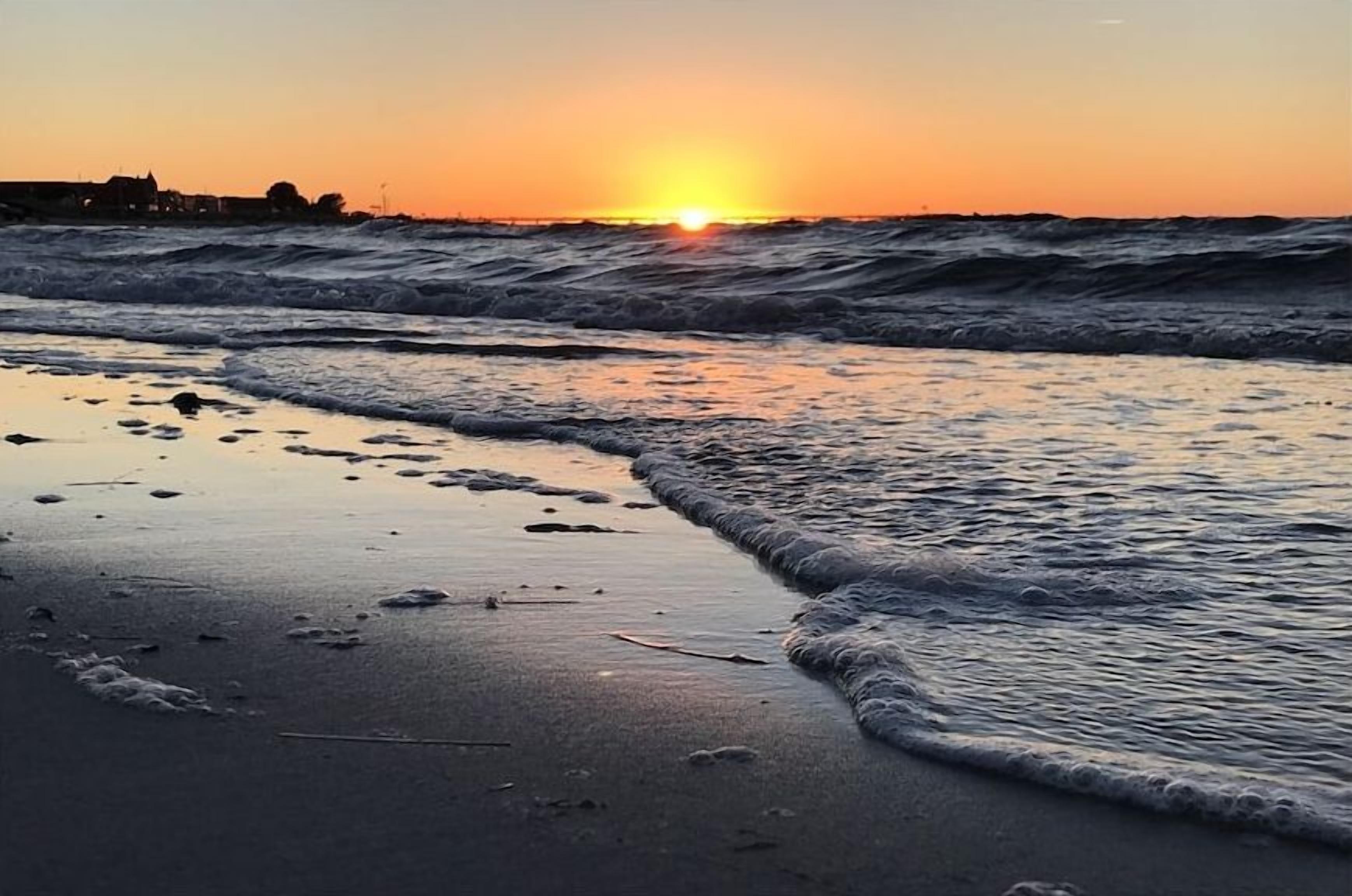 Une plage avec des vagues au coucher du soleil.