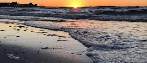 A beach with waves at sunset.