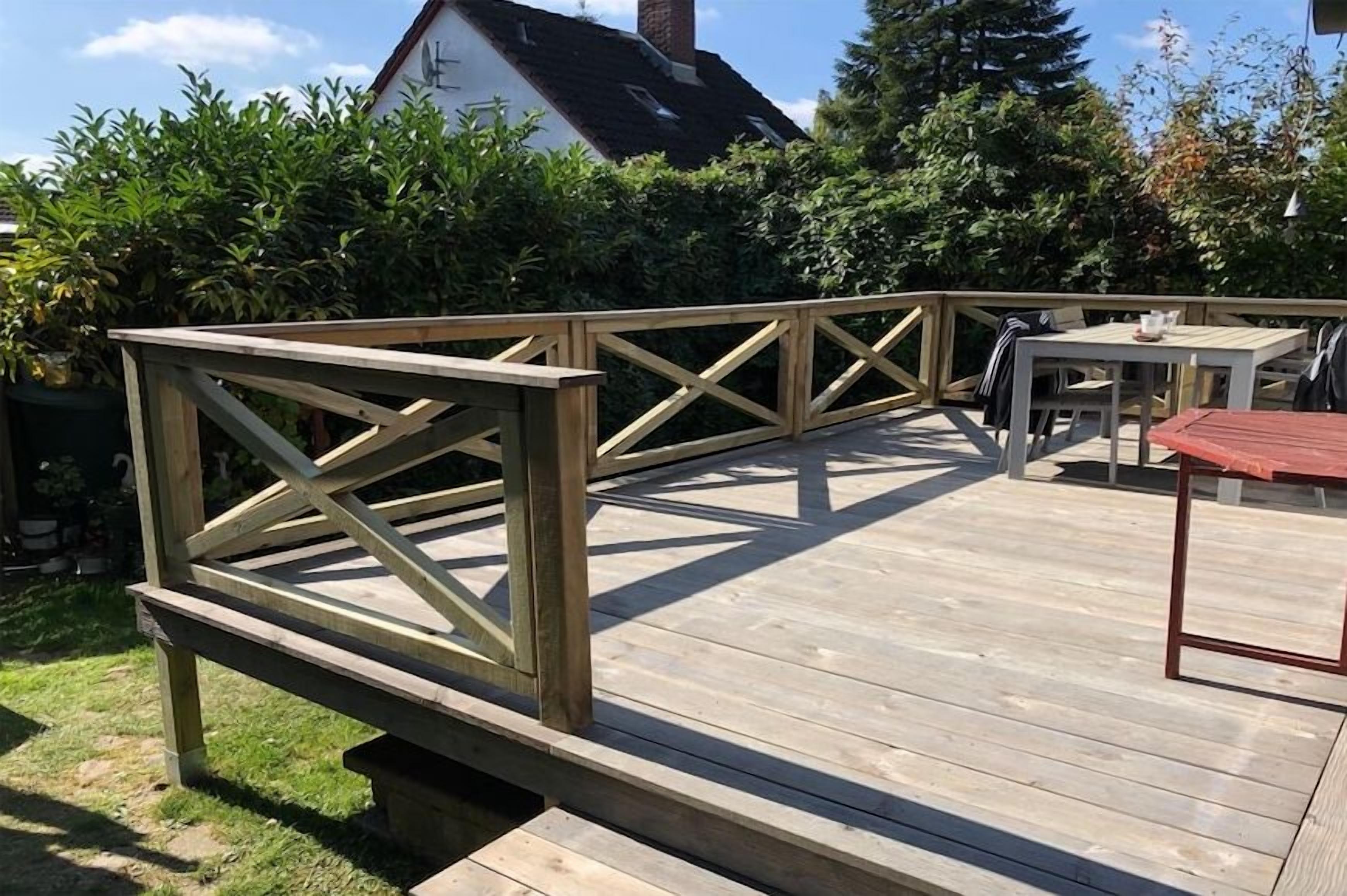 A wooden deck with a railing, a table, and chairs.