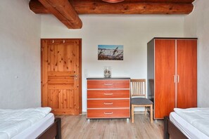 A bedroom with two beds, wooden wardrobe, a desk with drawers, a chair, and a painting on the wall. - Holiday apartment with 3 bedrooms (Börgerende)