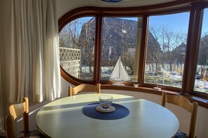 A dining area with a round table, chairs, and a view of a snowy landscape through large windows. - Holiday apartment with 2 bedrooms (Friedrichskoog-Spitze)