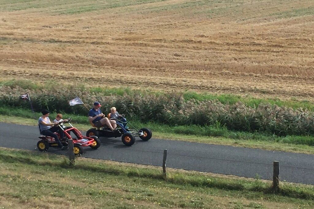 A rural road with a group of people on small, three-wheeled vehicles.