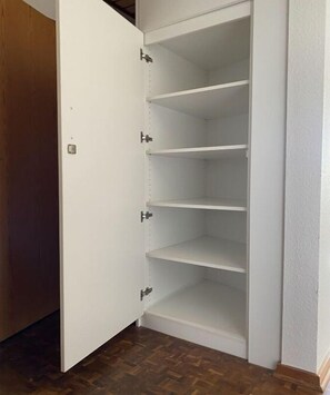 Un armari blanc amb diverses prestatgeries i una porta.