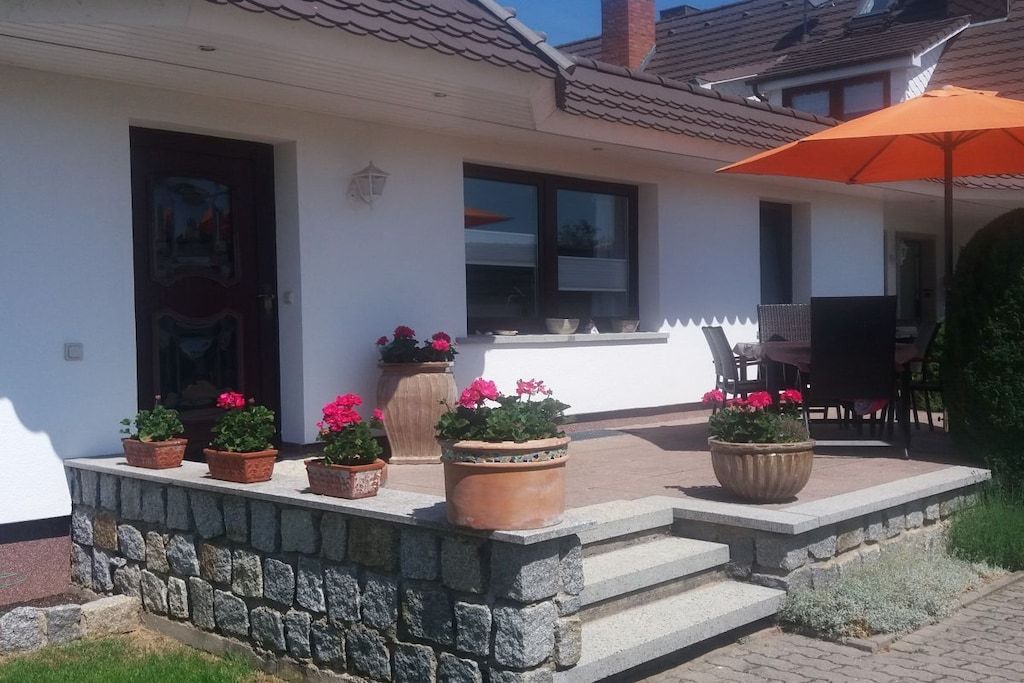 A house with a patio area, outdoor seating, and potted plants.