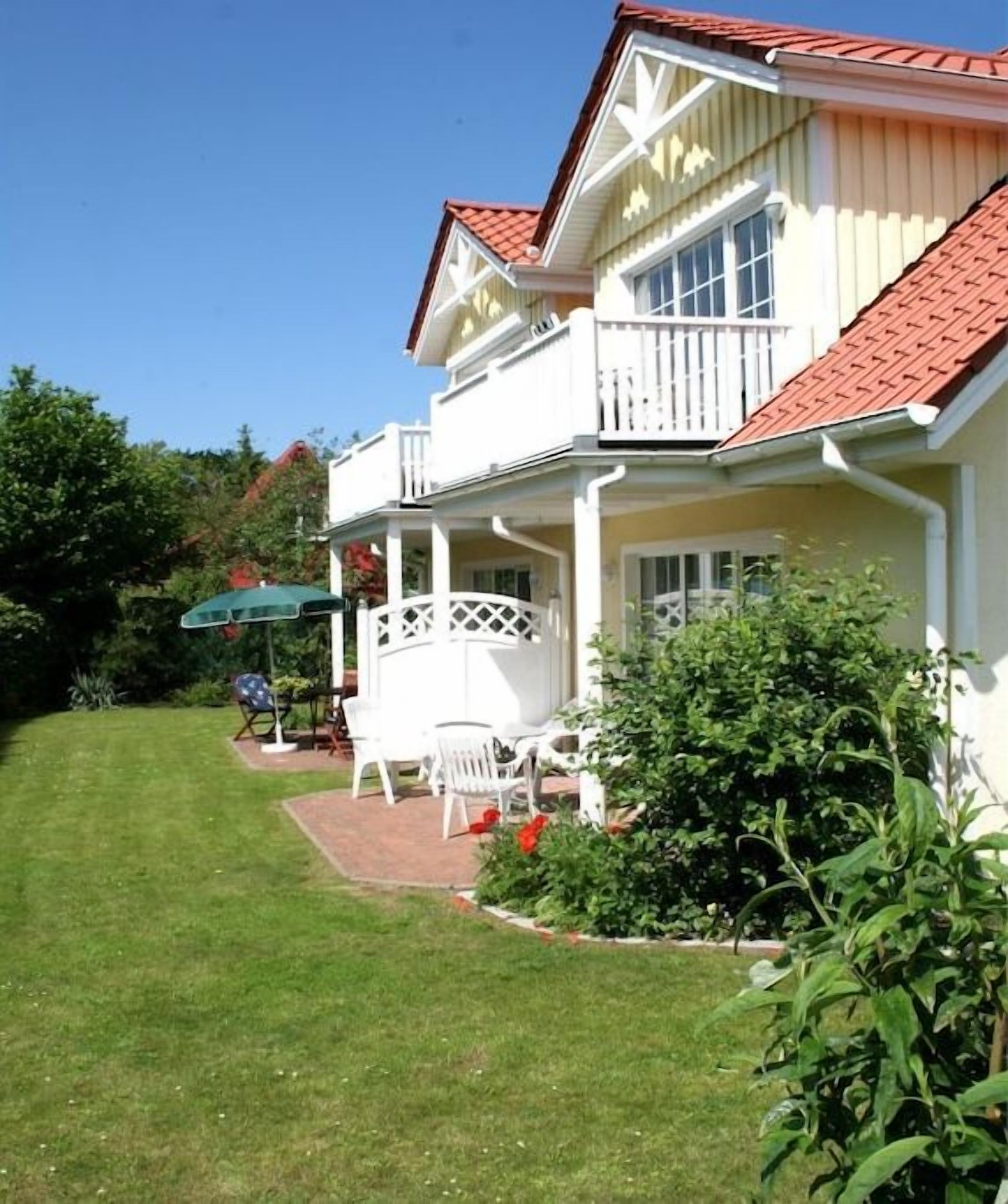 Uma casa de dois andares com varanda, alpendre coberto e gramado bem cuidado.