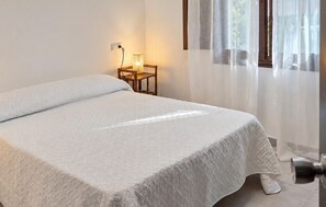 A neatly made bed with a white bedspread, a bedside table with a lamp, and a window with sheer curtains. - Amazing home in Adra with WiFi (Adra)