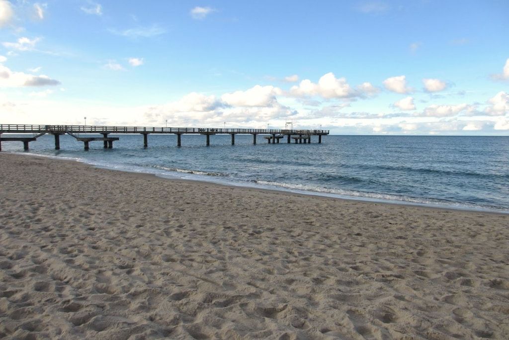 A beach with a pier extending into the water.