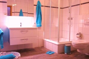 Une salle de bain avec une douche, des toilettes et un lavabo avec un miroir.