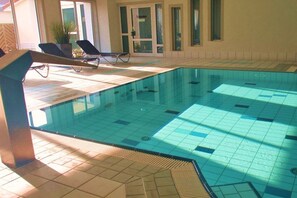 An indoor swimming pool with tiled flooring and lounge chairs. - Holiday apartment in Rerik with swimming pool (Rerik)