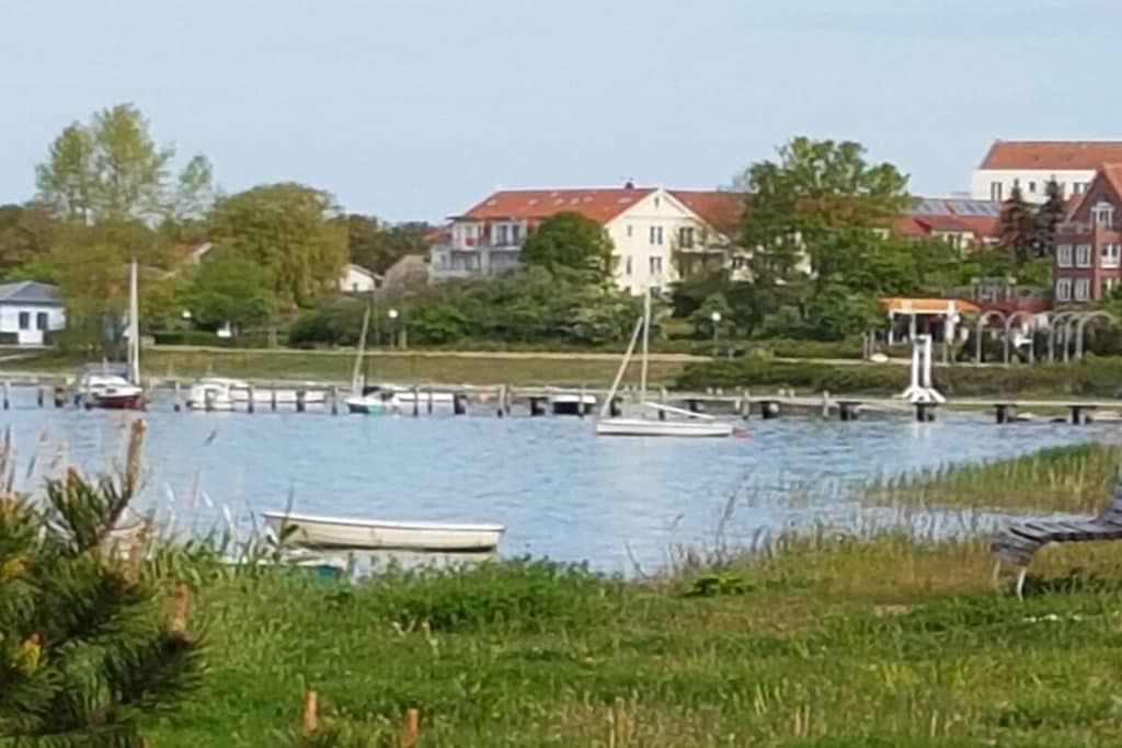 A waterfront view with boats docked, a pier, and buildings in the background.